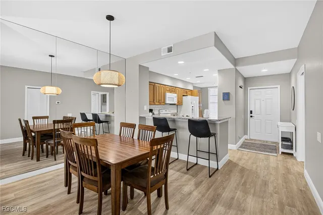 a view of a dining room and livingroom with furniture wooden floor a rug a fireplace and a chandelier
