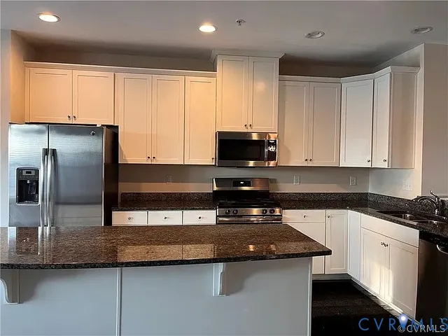 a kitchen with granite countertop a refrigerator and a stove top oven