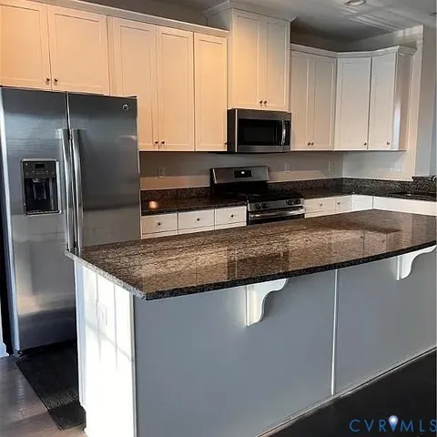 a kitchen with stainless steel appliances granite countertop a sink a stove a refrigerator a microwave a sink and a refrigerator