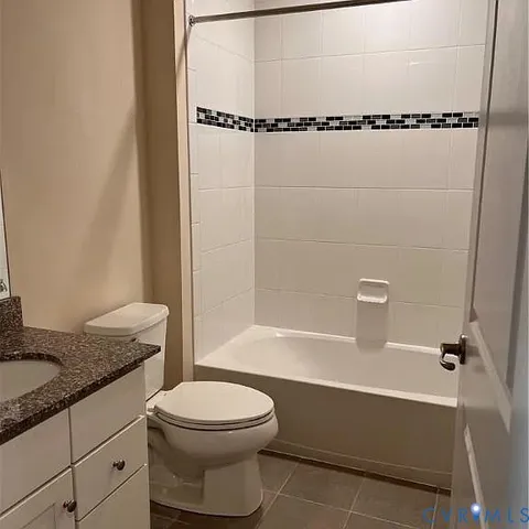 a bathroom with a granite countertop bathtub shower sink vanity and toilet