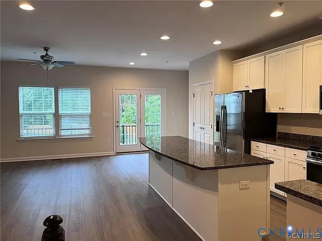 a kitchen with stainless steel appliances granite countertop a refrigerator a stove a microwave oven with white cabinets and wooden floor