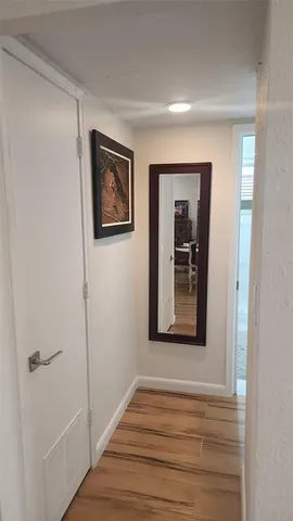 a view of a hallway with wooden floor and a bathroom