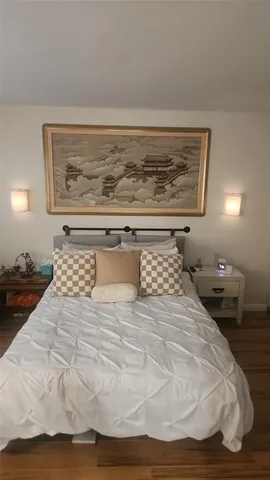 a bedroom with a bed and painting on the wall