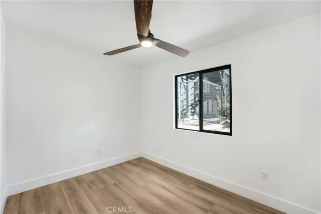 an empty room with a window and a ceiling fan
