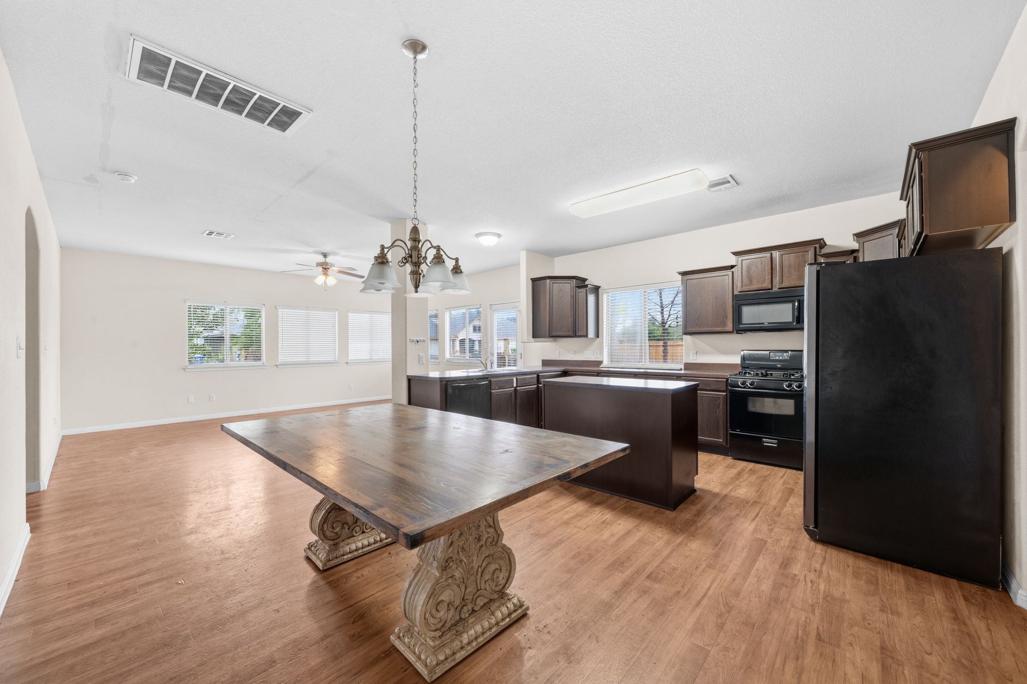 601 Silver Wing Drive Austin, TX 78725 - Photo 5 of 15 a kitchen with stainless steel appliances granite countertop a refrigerator a sink dishwasher a stove and a dining table with wooden floor