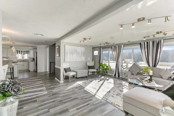 a living room with furniture large window and wooden floor