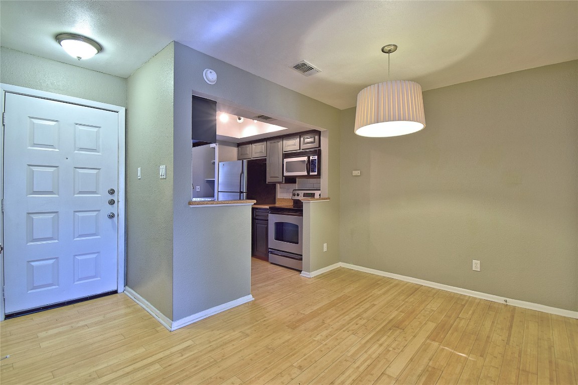 7635 Guadalupe Street, Unit 803 Austin, TX 78752 - Photo 4 of 16 an empty room with a kitchen and chandelier fan