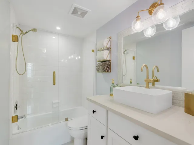 a bathroom with a sink a toilet a mirror and shower