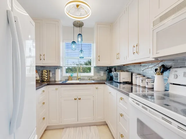 a kitchen with granite countertop white cabinets and white appliances