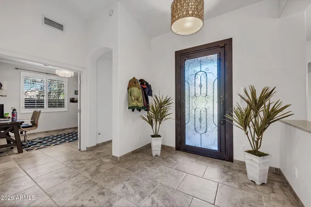 a living room with large couches chandelier and a dining table with wooden floor