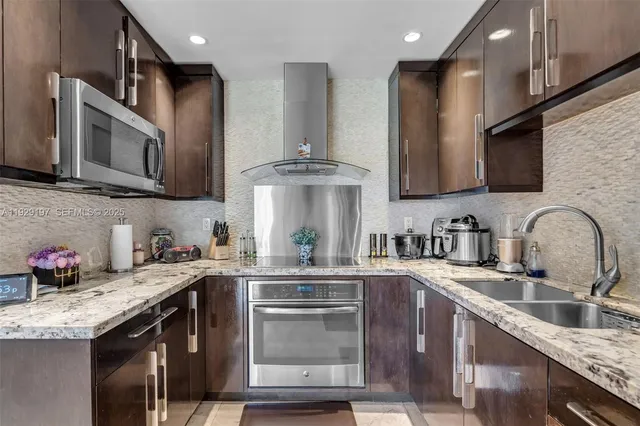 a kitchen with granite countertop a sink stainless steel appliances and cabinets