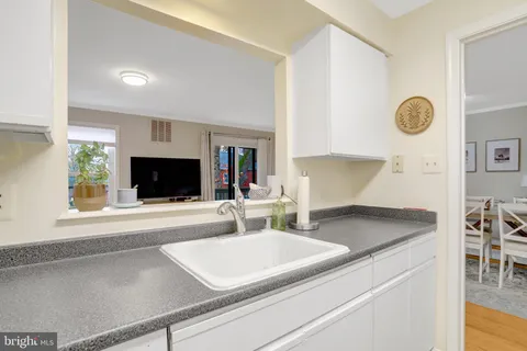 a kitchen with a sink a microwave a stove and white cabinets with wooden floor