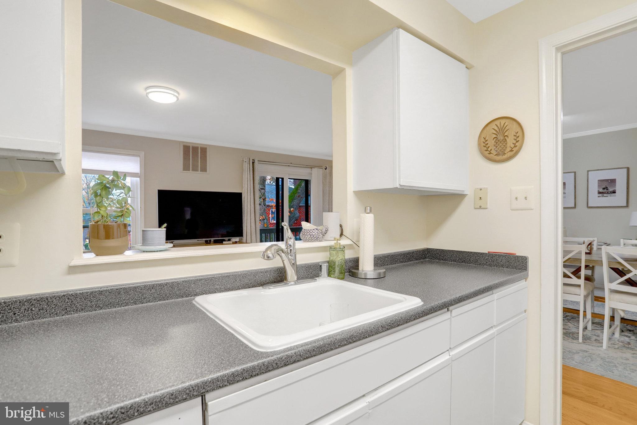 2101 North Rolfe Street, Unit C Arlington, VA 22209 - Photo 10 of 26 a kitchen with a sink a microwave a stove and white cabinets with wooden floor