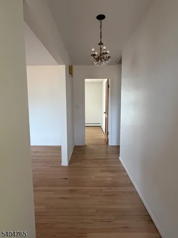 a view of a hallway with wooden floor and chandelier
