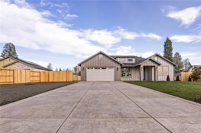 a view of house next to a yard with big trees