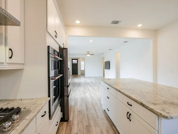 a view of a kitchen island wooden floor and stainless steel appliances