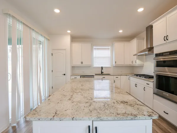 a large kitchen with stainless steel appliances granite countertop a stove a sink and a refrigerator