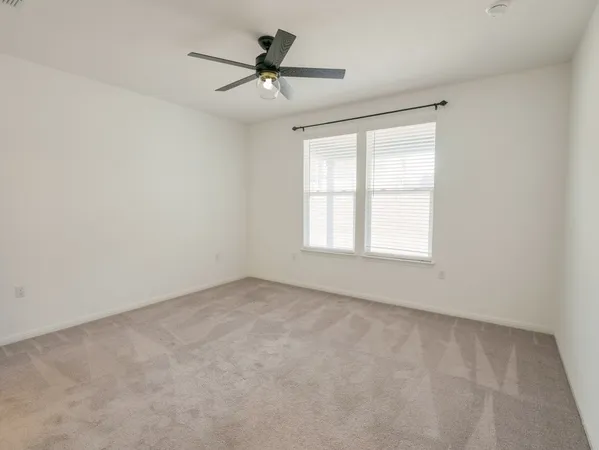 an empty room with a window and a fan