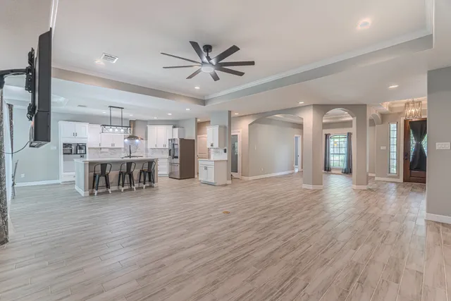 a view of an empty room with a kitchen and a ceiling fan