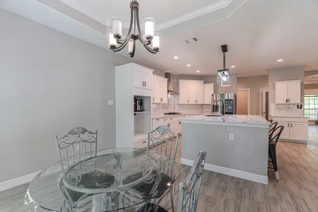 a room with stainless steel appliances kitchen island granite countertop a table chairs and a refrigerator