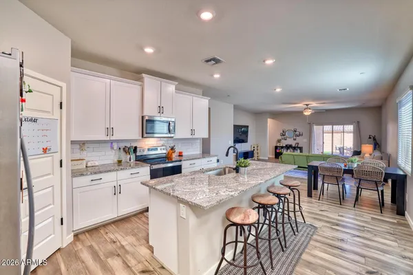 a kitchen with white cabinets sink and chairs