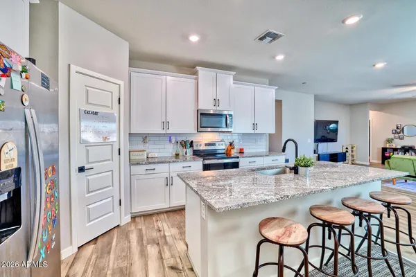 a kitchen with granite countertop white cabinets and refrigerator