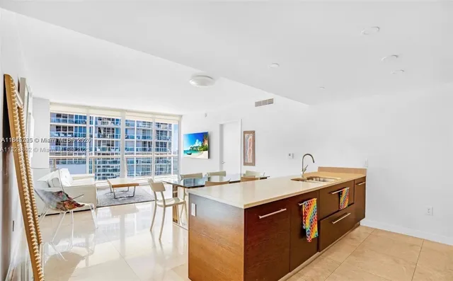 a living room with stainless steel appliances kitchen island granite countertop a sink and cabinets