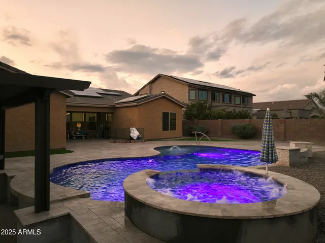a view of swimming pool with red chairs in front of house