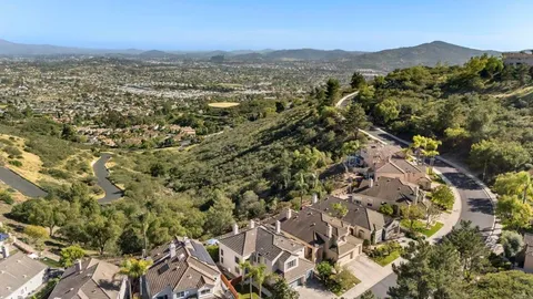 an aerial view of residential houses with outdoor space and trees