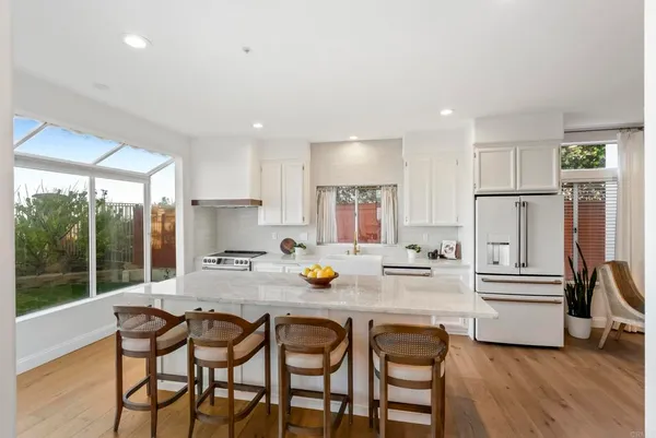 a kitchen with a refrigerator a stove a sink and a dining table with wooden floor