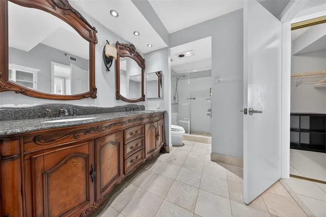 a spacious bathroom with a granite countertop sink mirror vanity and a toilet