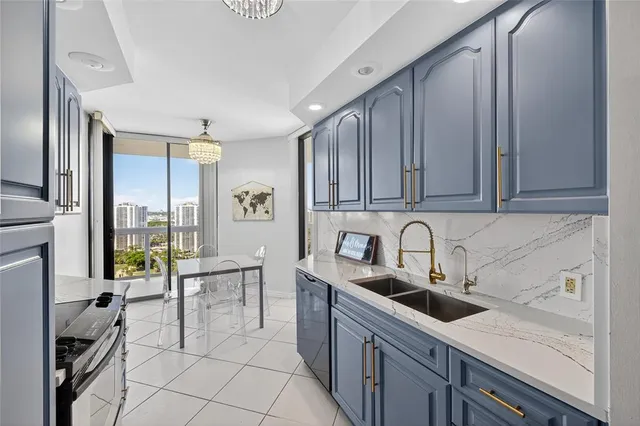 a kitchen with stainless steel appliances a sink a stove a refrigerator cabinets and living room view