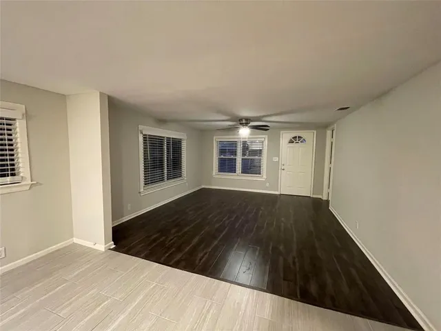 a view of empty room with wooden floor and fan