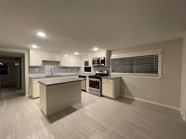 a kitchen with granite countertop a stove top oven and cabinets