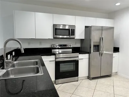 a kitchen with granite countertop a stove a sink and a microwave