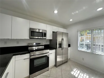 a kitchen with granite countertop a refrigerator and a stove top oven