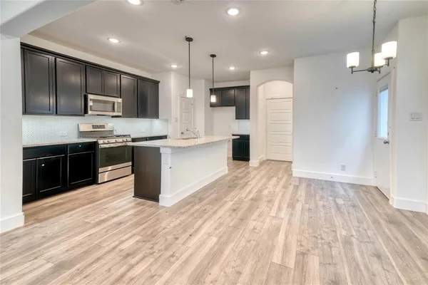 a large kitchen with stainless steel appliances kitchen island granite countertop a sink refrigerator and cabinets