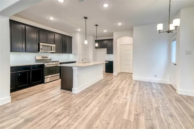 a large kitchen with stainless steel appliances kitchen island granite countertop a sink refrigerator and cabinets