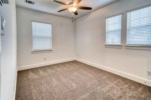 an empty room with windows and fan