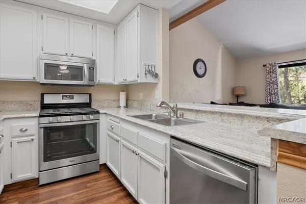 a kitchen with granite countertop a sink stainless steel appliances and white cabinets