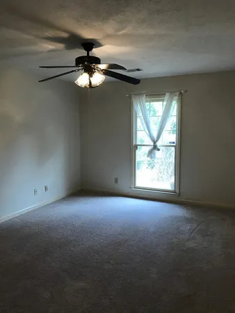 an empty room with a window and a fan