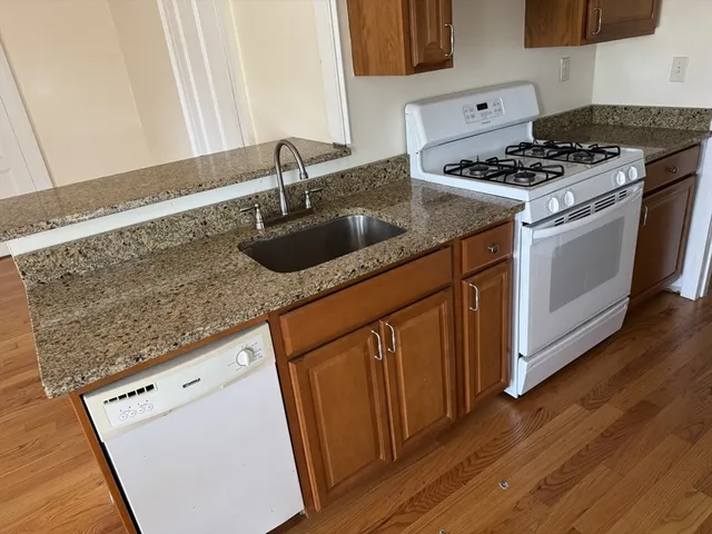 a kitchen with granite countertop a sink stove and cabinets