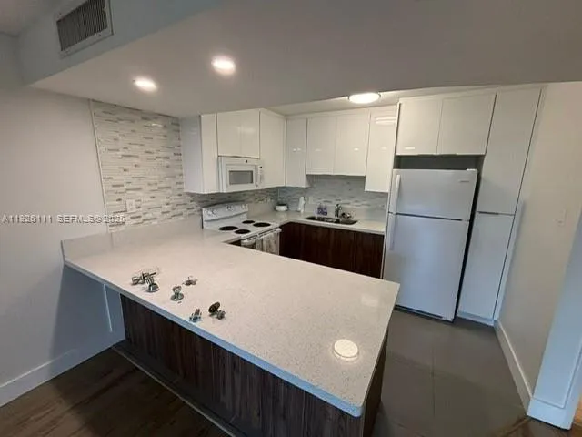 a kitchen with stainless steel appliances a refrigerator a sink and white cabinets