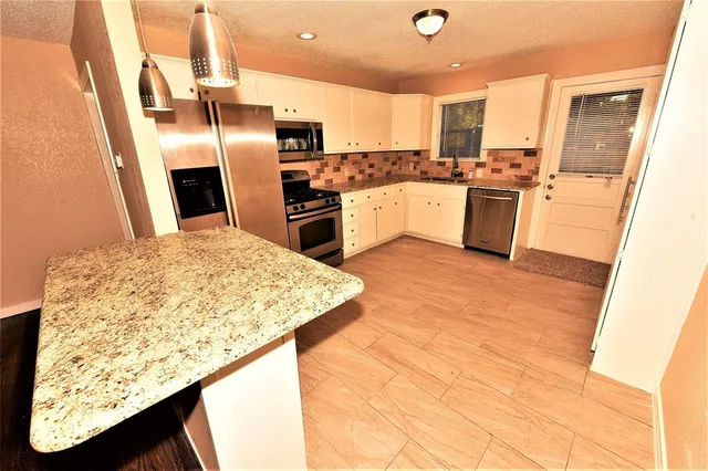 a kitchen with stainless steel appliances granite countertop a sink refrigerator and cabinets