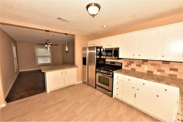 a large kitchen with cabinets and stainless steel appliances