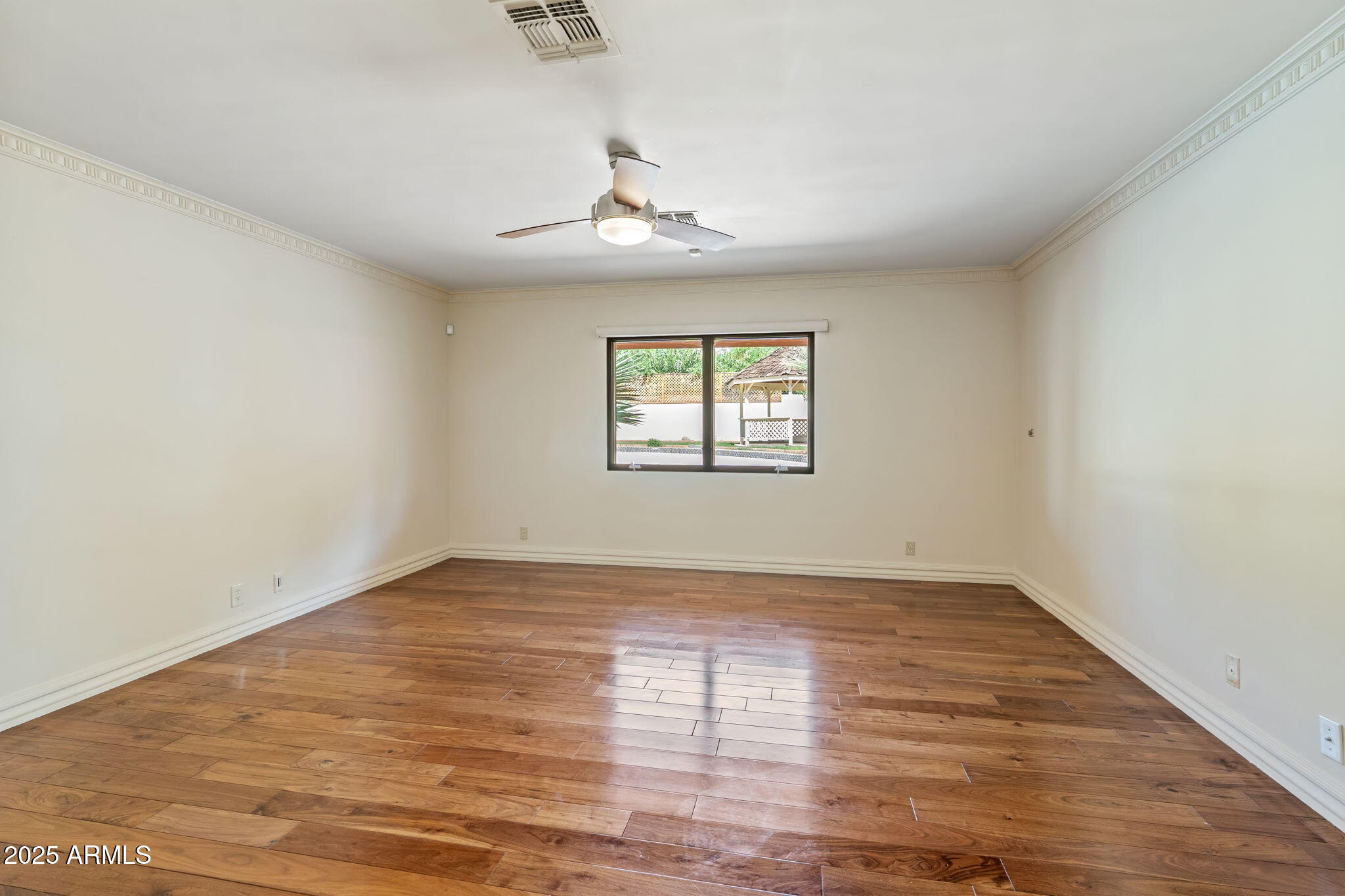 5310 East Camelback Road Phoenix, AZ 85018 - Photo 22 of 50 an empty room with wooden floor chandelier fan and windows