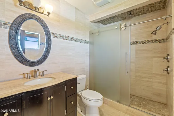 a bathroom with a granite countertop sink a mirror and a toilet