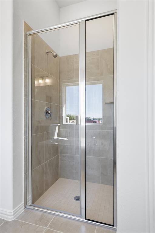 2529 Rivers W Road Anna, TX 75409 - Photo 27 of 40 Enclosed shower with clear glass door, tiled walls, built-in shelf, frosted window, and overhead lighting