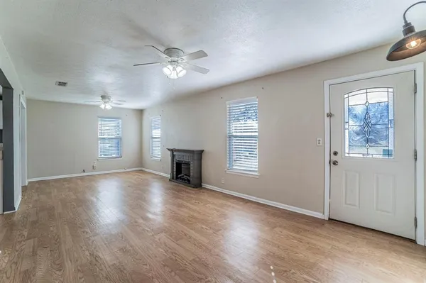 a view of an empty room with a window and wooden floor