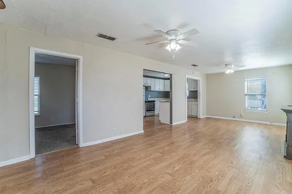 a view of an empty room with window and wooden floor